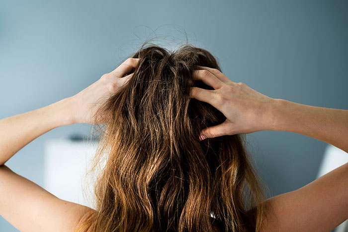 mulher de costas com as mãos na cabeça