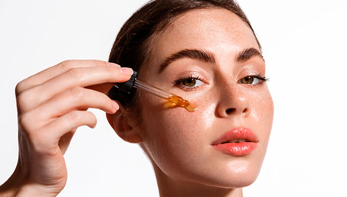 mulher aplicando óleo facial no rosto