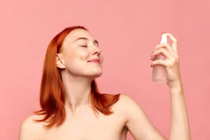 mulher utilizando spray fixador de maquiagem
