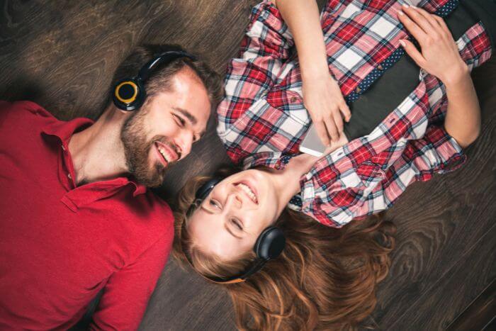 casal de namorados ouvindo música em fones de ouvidos deitados no chão