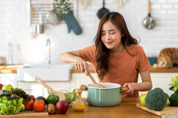 mulher cozinhando com legumes e verduras