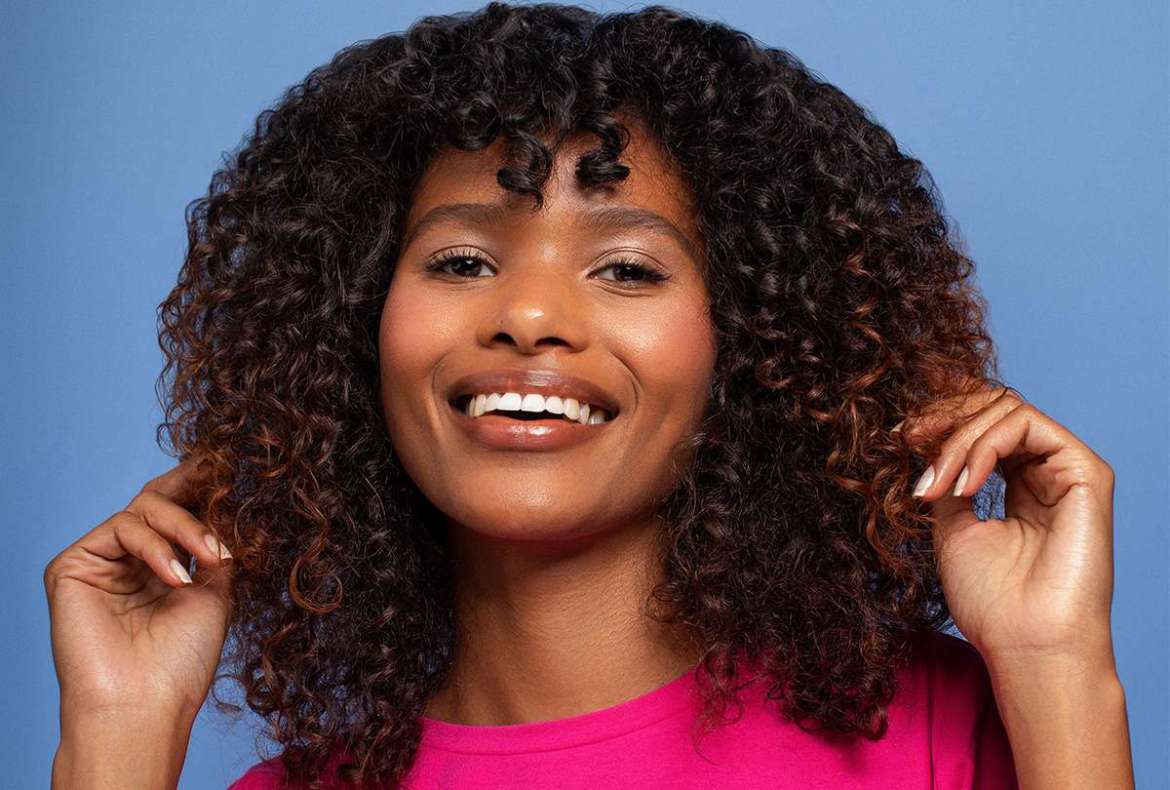 mulher negra de cabelos cacheados com franja